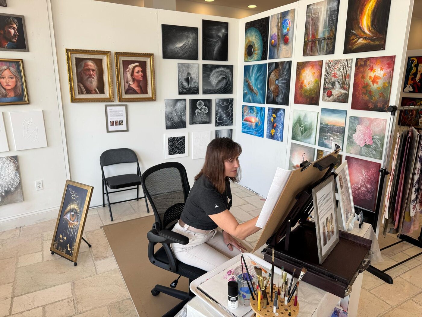 Irina Page painting in her studio, surrounded by finished works